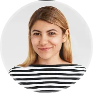 Smiling woman with straight blonde hair wearing a black and white striped shirt on light background.