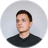 Portrait of a young man with short dark hair wearing a black shirt against a plain background.